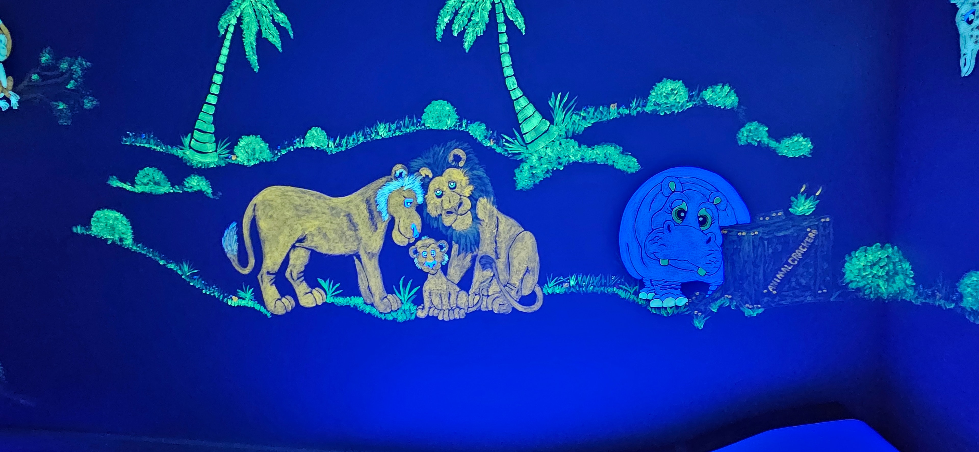 Jungle room glowing with lions, hippos, palm trees and safari animals under black light