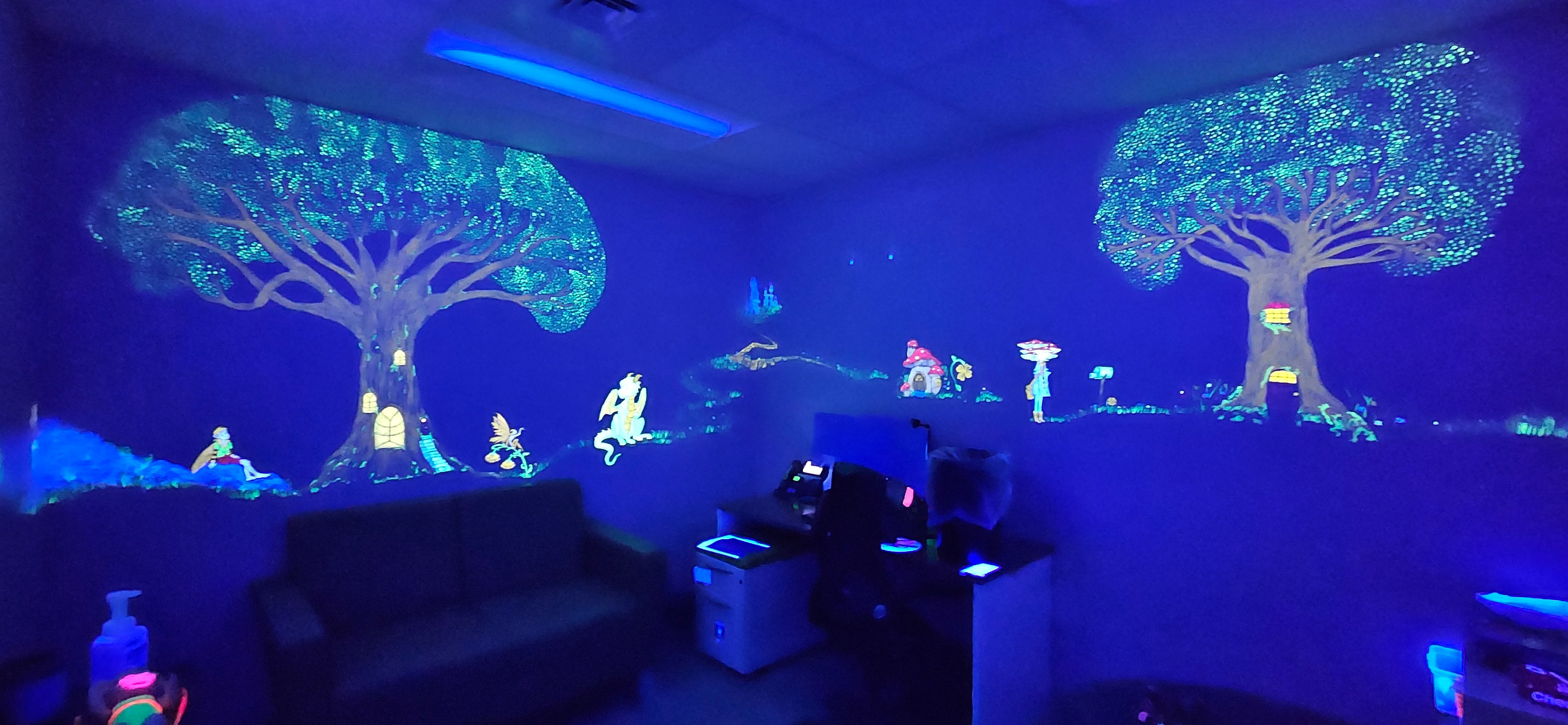 Fantasy room glowing with magical fairy trees, mushroom houses and woodland creatures under black light