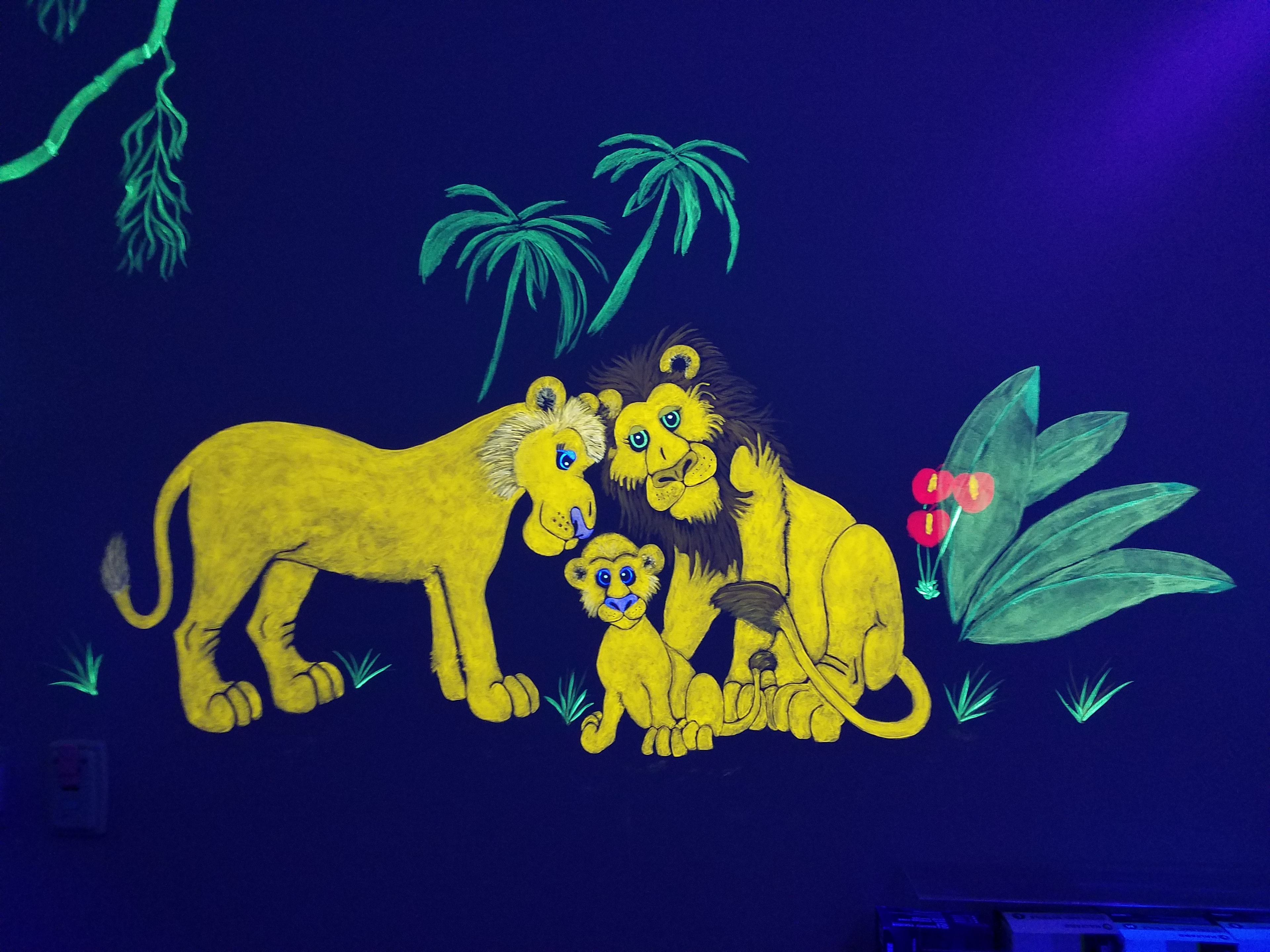 Glowing lion family painted on the Jungle Room wall under black light