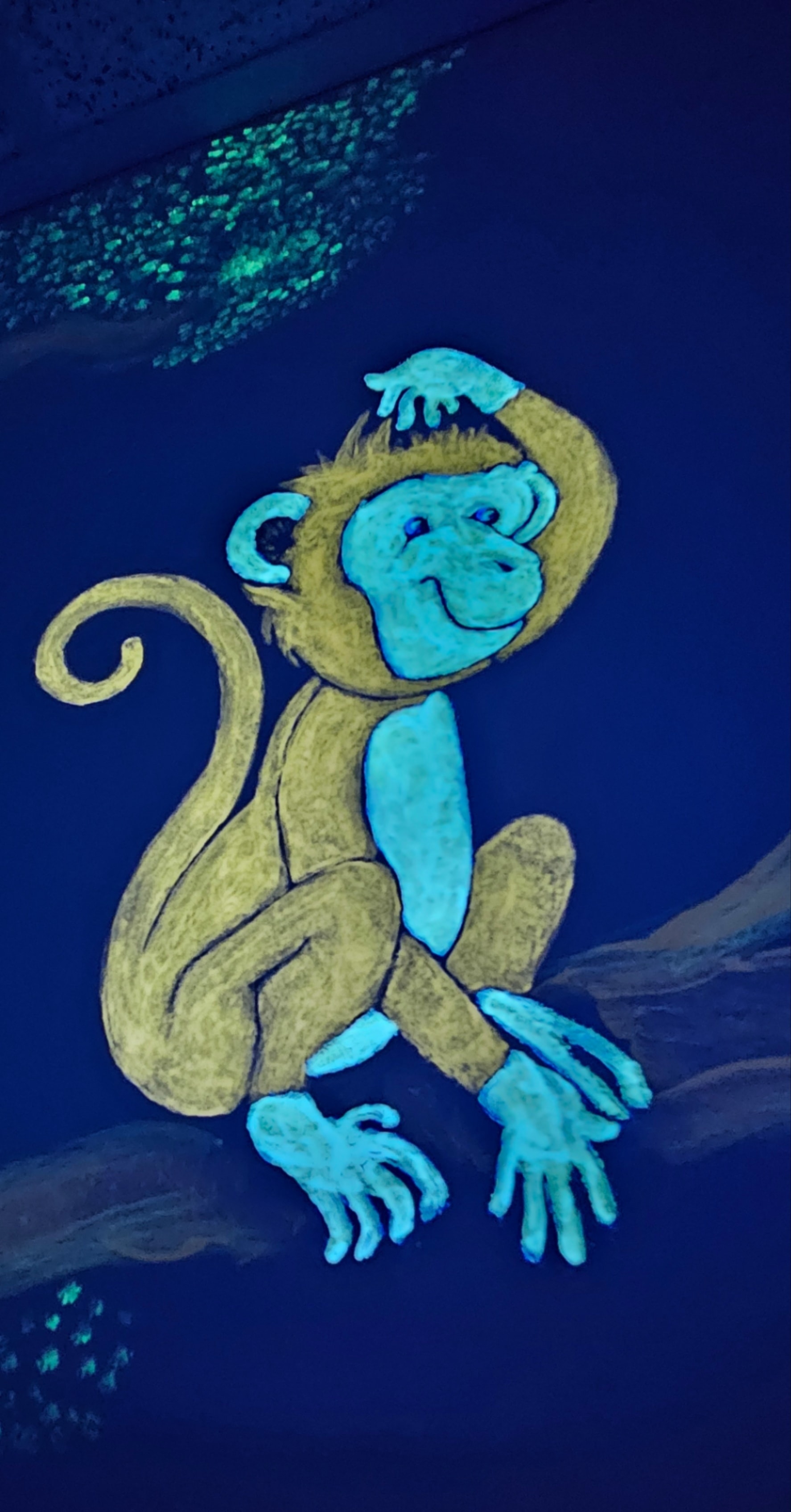 Glowing monkey with cyan face painted on the Jungle Room wall under black light