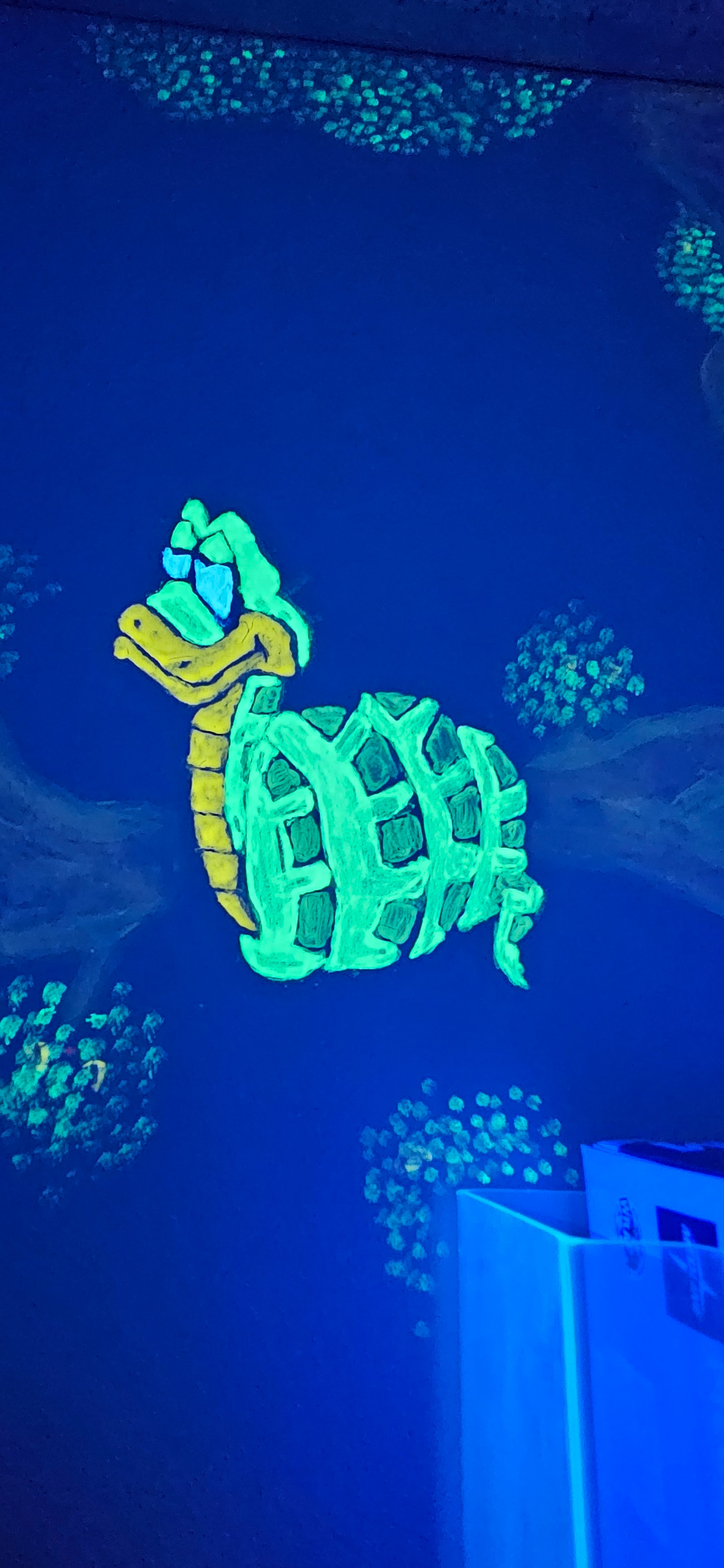 Glowing coiled snake painted on the Jungle Room wall under black light