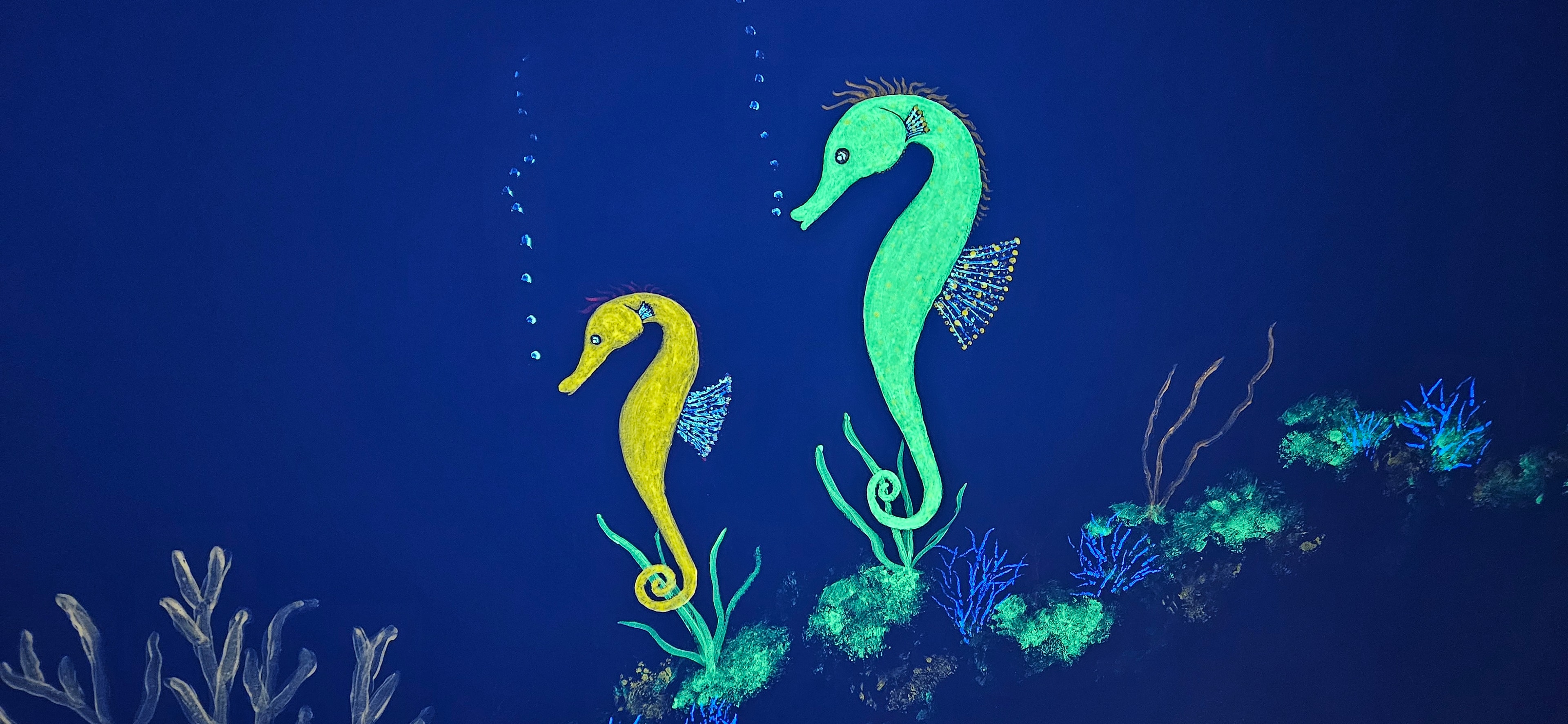 Ocean room wall glowing with yellow and green seahorses under black light