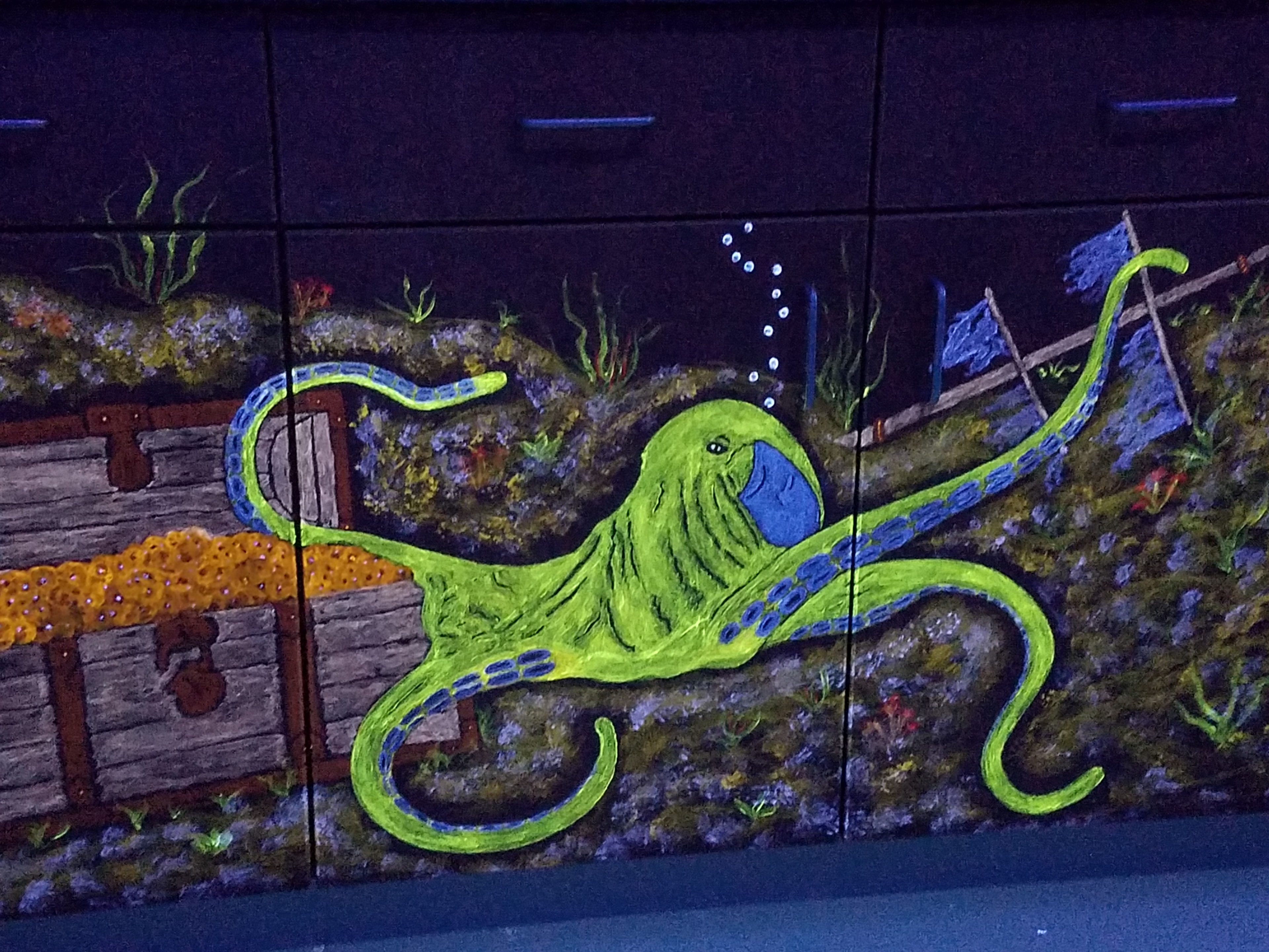 Vibrant neon-green octopus with blue accents among shipwreck and marine elements under black light